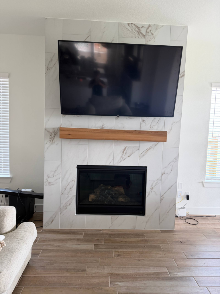 Premium fireplace TV mounting with marble tile wall and clean centered finish in Houston