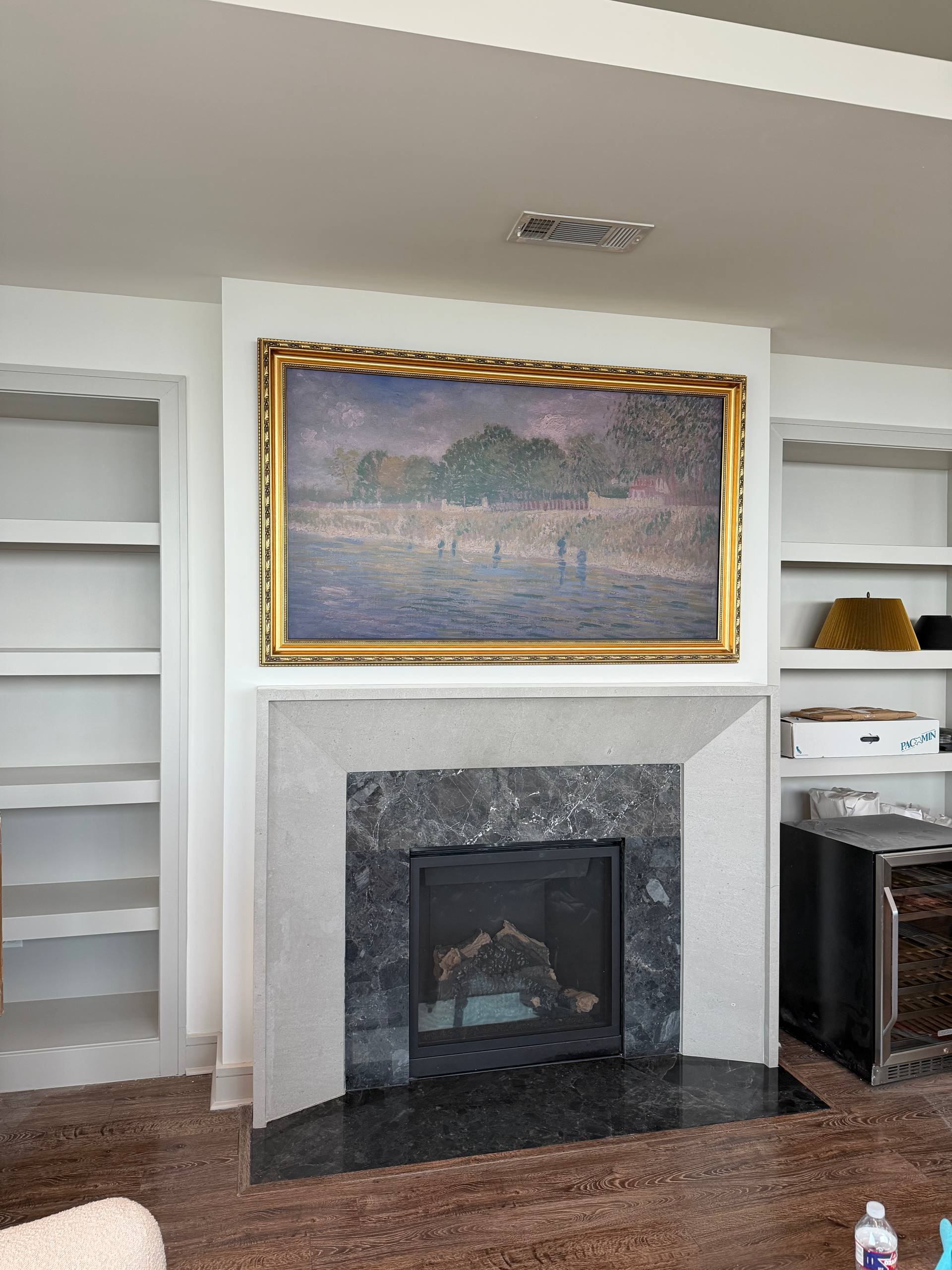 Fireplace wall with framed artwork before TV installation in Houston