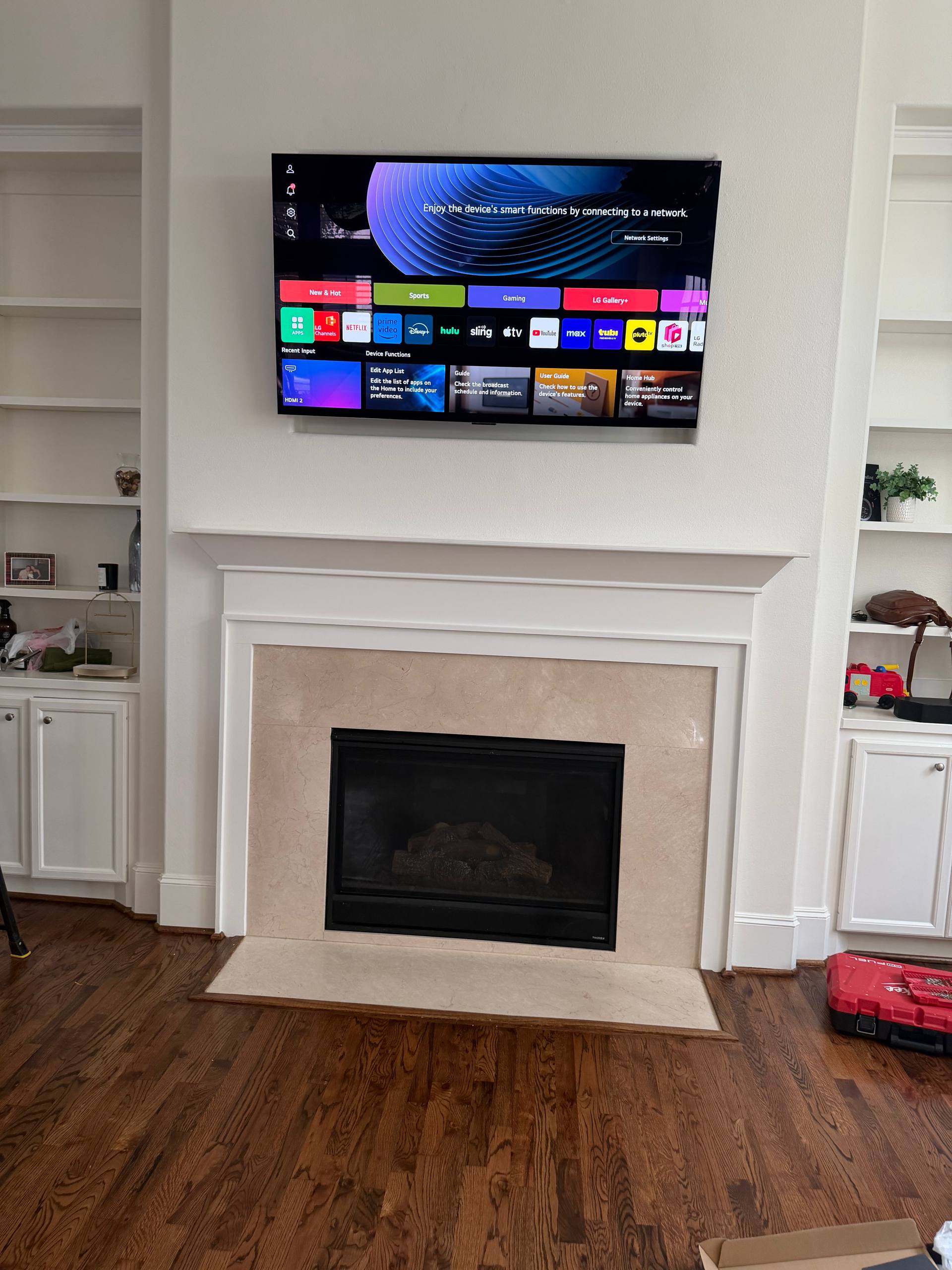 TV mounted above a white fireplace with built-in shelves and concealed cables in Houston